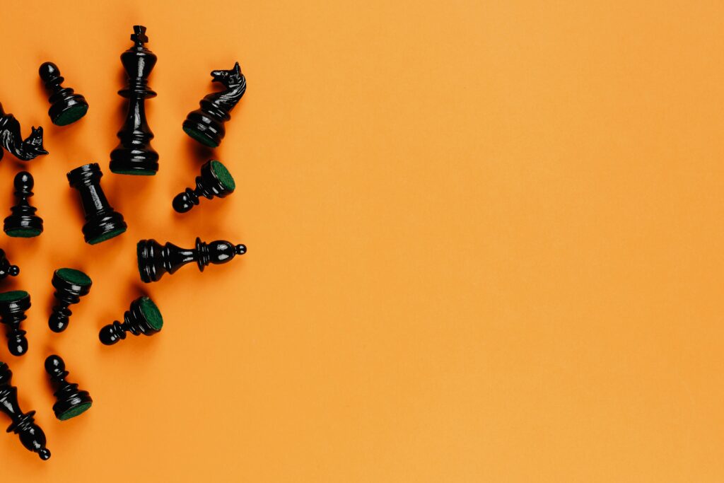Scattered black chess pieces on an orange background, perfect for strategy concepts.